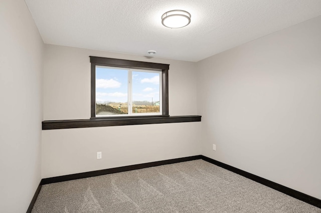 empty room featuring carpet, a textured ceiling, and baseboards