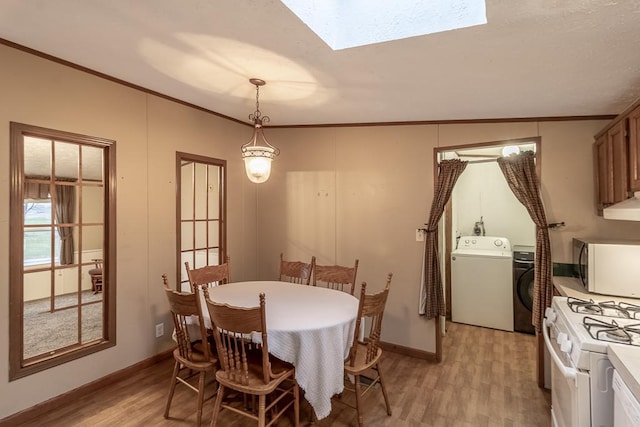 dining room with washing machine and dryer, light wood-type flooring, crown molding, and lofted ceiling with skylight