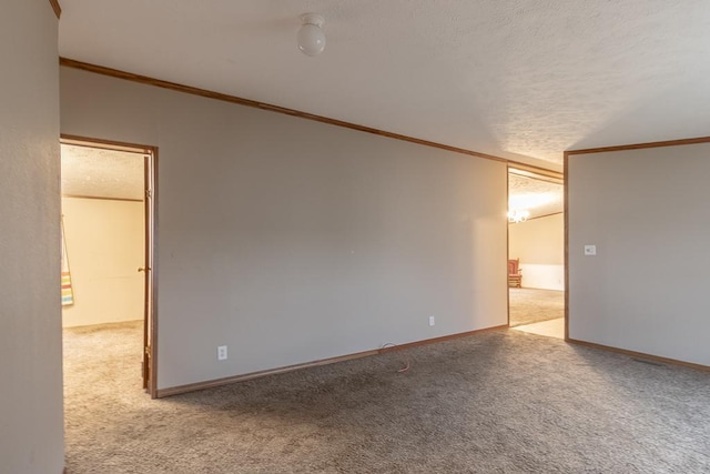 carpeted empty room with a textured ceiling and crown molding