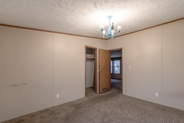 unfurnished bedroom with a textured ceiling, carpet floors, a closet, and a notable chandelier