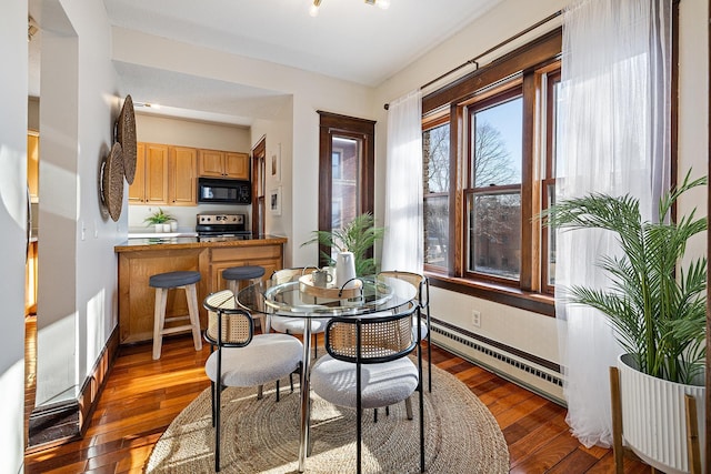 dining area with dark hardwood / wood-style floors and a baseboard heating unit