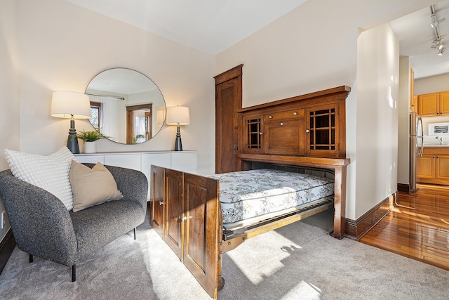 bedroom featuring stainless steel fridge and hardwood / wood-style floors