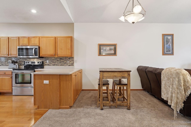 kitchen with hanging light fixtures, light hardwood / wood-style flooring, decorative backsplash, kitchen peninsula, and stainless steel appliances