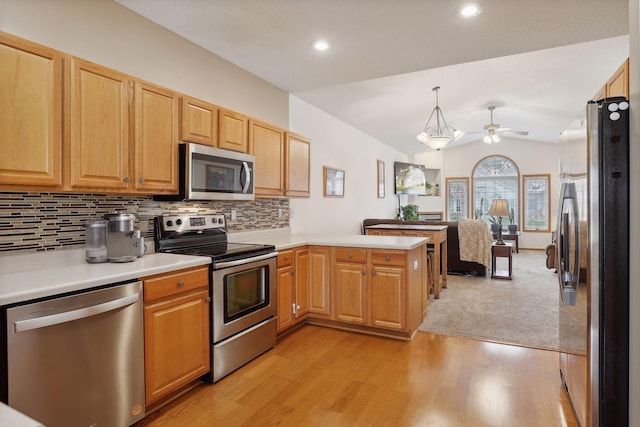 kitchen featuring stainless steel appliances, kitchen peninsula, decorative light fixtures, lofted ceiling, and light wood-type flooring