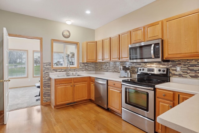 kitchen featuring sink, tasteful backsplash, light hardwood / wood-style flooring, a textured ceiling, and appliances with stainless steel finishes