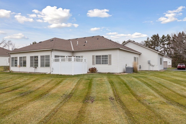 rear view of property with cooling unit and a yard