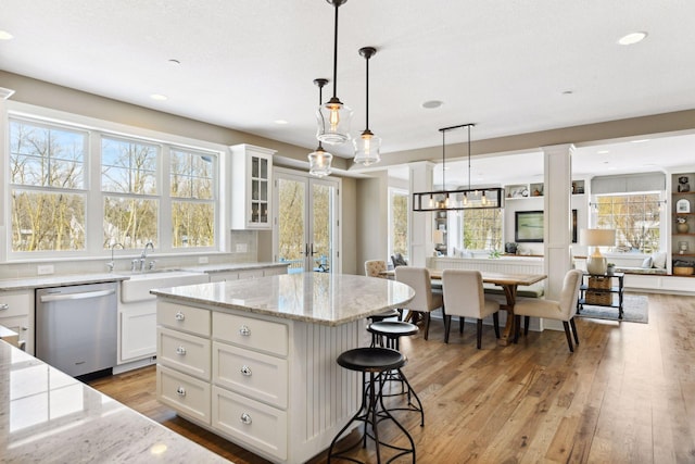 21360 Christmas Ln, Shorewood, MN 55331 - kitchen featuring stainless steel dishwasher, white cabinetry, a breakfast bar, open floor plan, and light wood finished floors