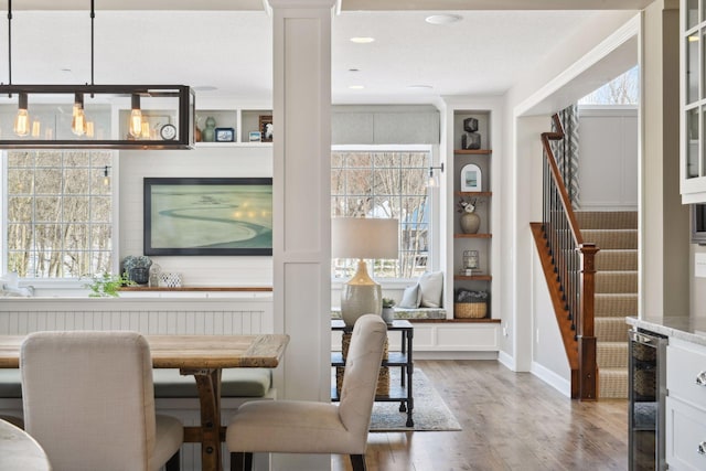 21360 Christmas Ln, Shorewood, MN 55331 - dining room with light wood-style floors, built in features, ornate columns, stairs, and wine cooler