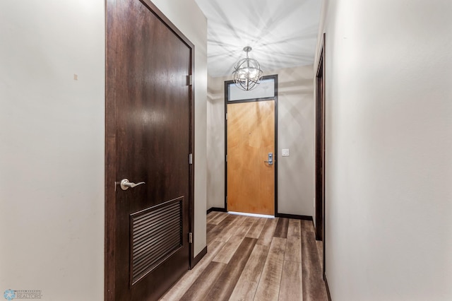 hallway featuring wood-type flooring and a notable chandelier