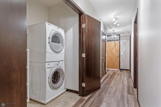 laundry room with stacked washer / drying machine and light hardwood / wood-style flooring