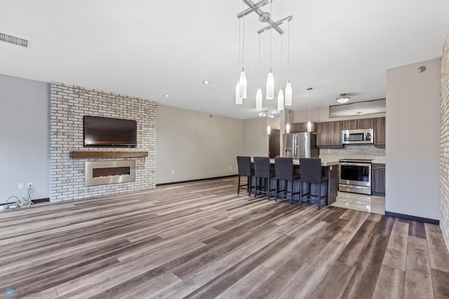 kitchen with stainless steel appliances, light hardwood / wood-style flooring, decorative light fixtures, a breakfast bar, and a kitchen island