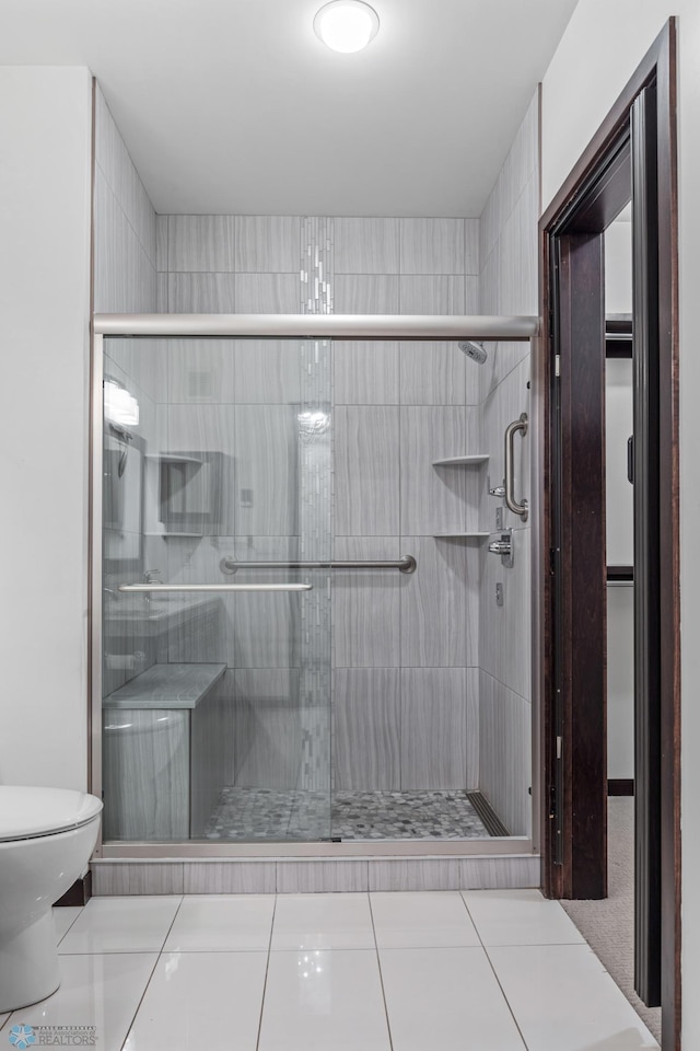 bathroom featuring tile patterned flooring, toilet, and walk in shower