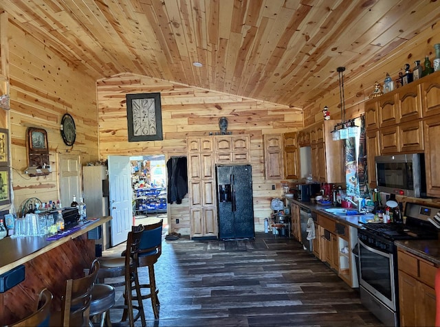 kitchen with wood walls, dark hardwood / wood-style flooring, lofted ceiling, and appliances with stainless steel finishes