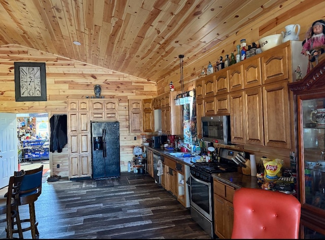 kitchen featuring wooden walls, dark hardwood / wood-style floors, vaulted ceiling, and appliances with stainless steel finishes