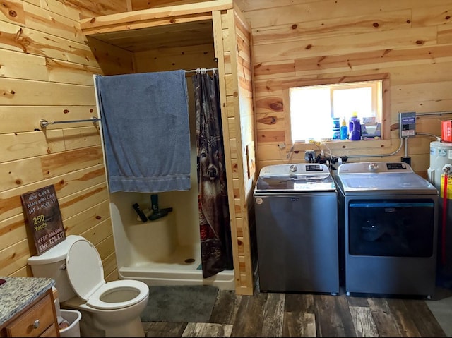 clothes washing area with dark hardwood / wood-style flooring, wood walls, and washing machine and dryer