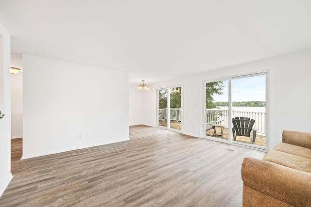 living area with a chandelier, wood finished floors, visible vents, and baseboards