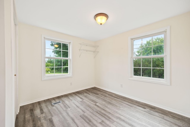 empty room with visible vents, baseboards, and wood finished floors