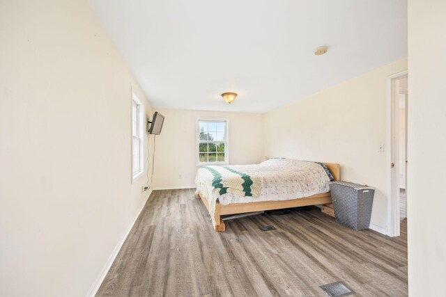 bedroom featuring visible vents, baseboards, and wood finished floors