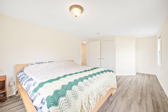 bedroom with a closet, wood finished floors, and baseboards