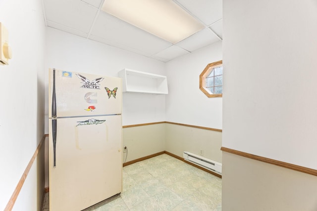 kitchen with a baseboard heating unit, freestanding refrigerator, a paneled ceiling, and baseboards