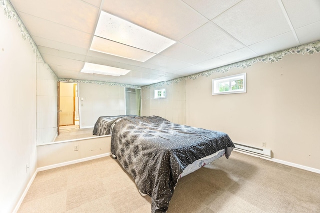 bedroom with light carpet, baseboards, baseboard heating, and a drop ceiling