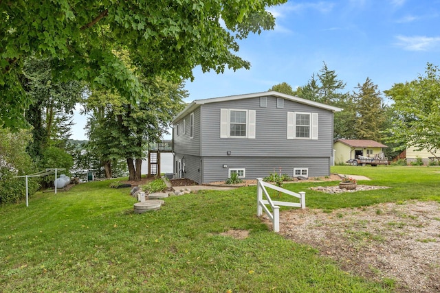 back of house featuring stairway, a fire pit, and a yard