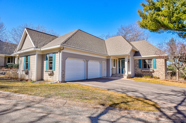 view of front of house with driveway, roof with shingles, a front lawn, a garage, and brick siding