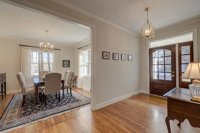 dining area featuring baseboards, an inviting chandelier, wood finished floors, and crown molding