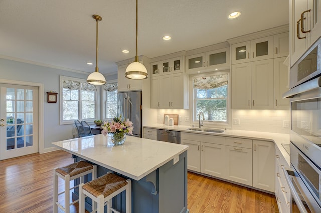 kitchen featuring a sink, a kitchen breakfast bar, backsplash, stainless steel appliances, and light wood finished floors