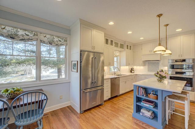 kitchen with light wood finished floors, a sink, stainless steel appliances, light countertops, and white cabinetry