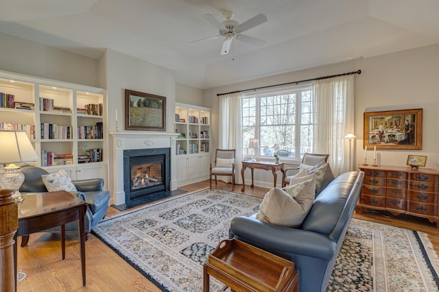 living room with a high end fireplace, baseboards, a ceiling fan, and wood finished floors