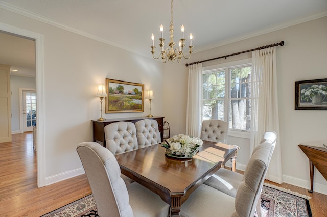 dining room featuring a chandelier, baseboards, crown molding, and light wood-style floors