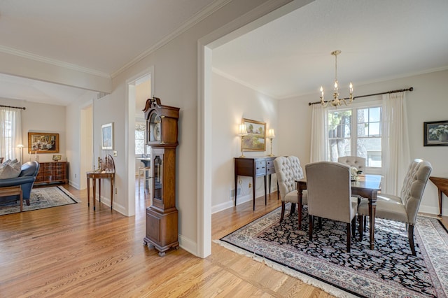 dining room featuring a chandelier, light wood-style flooring, baseboards, and ornamental molding