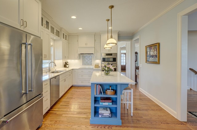 kitchen with a sink, light wood-style floors, backsplash, and appliances with stainless steel finishes