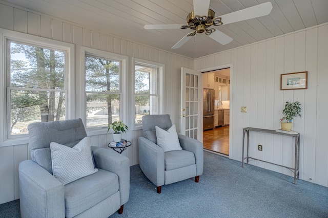 living area with carpet flooring, wood ceiling, and a ceiling fan