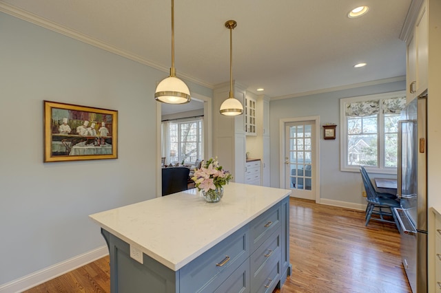 kitchen featuring high end fridge, wood finished floors, hanging light fixtures, and ornamental molding