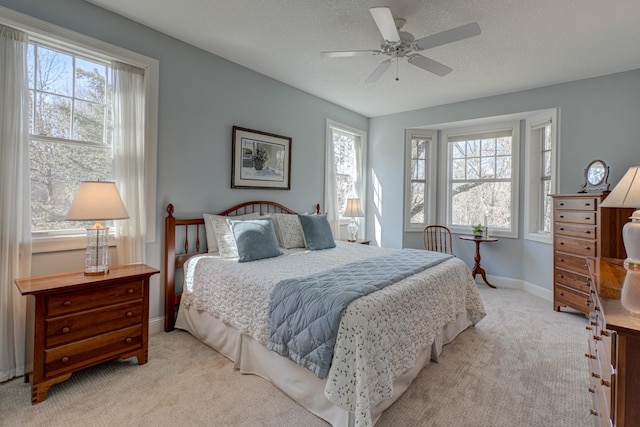 bedroom with light colored carpet, baseboards, and a textured ceiling