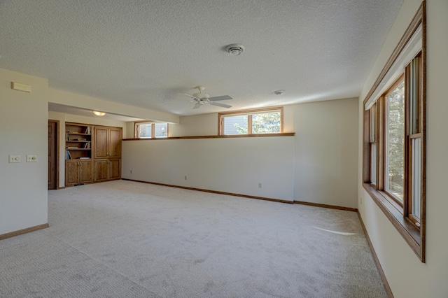 empty room with ceiling fan, baseboards, a wealth of natural light, and light carpet