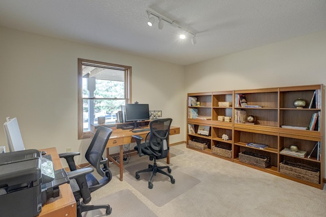 carpeted office with baseboards, a textured ceiling, and track lighting