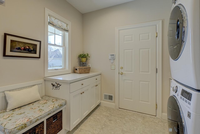 laundry area featuring visible vents, cabinet space, baseboards, and stacked washer / dryer