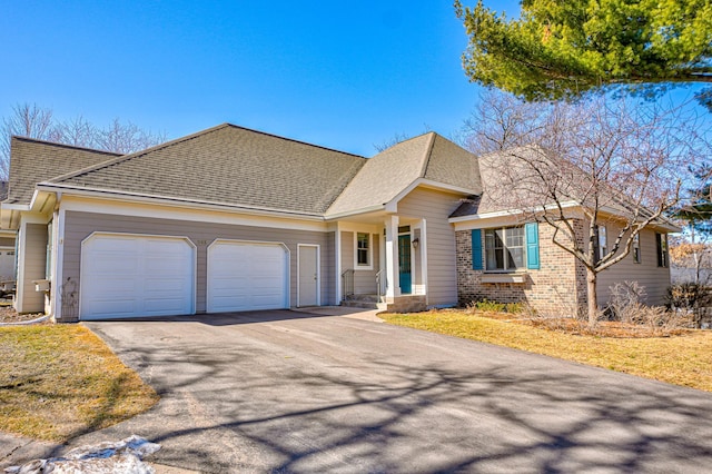 view of front of home featuring brick siding, driveway, an attached garage, and roof with shingles