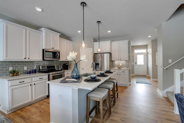 kitchen with white cabinets, appliances with stainless steel finishes, and light hardwood / wood-style flooring