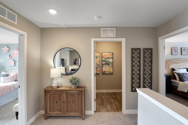 corridor with light carpet and a textured ceiling