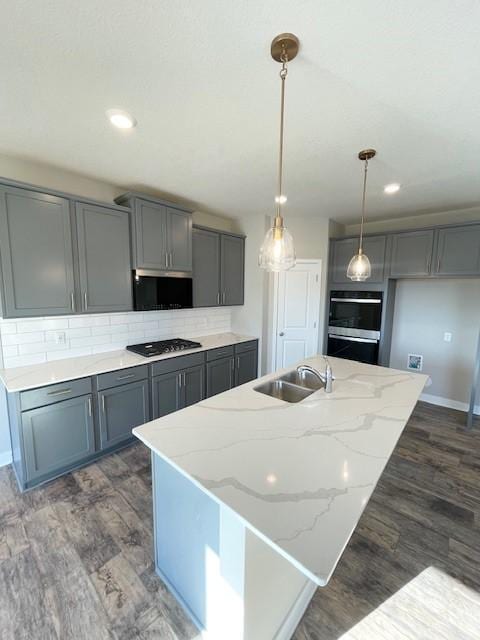 kitchen featuring sink, dark hardwood / wood-style floors, backsplash, black gas stovetop, and pendant lighting