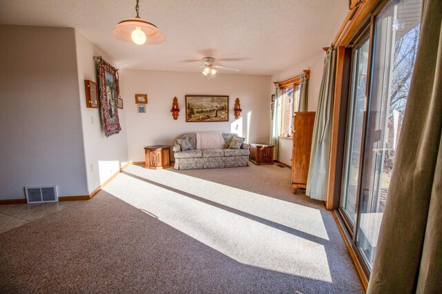 unfurnished living room featuring ceiling fan, carpet floors, and a textured ceiling