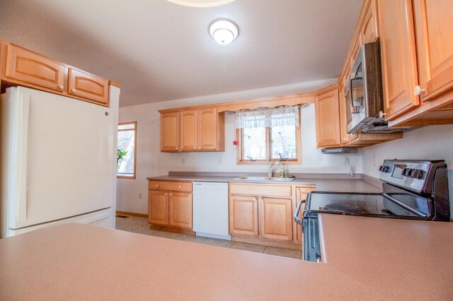 kitchen featuring appliances with stainless steel finishes, light tile patterned floors, light brown cabinetry, and sink