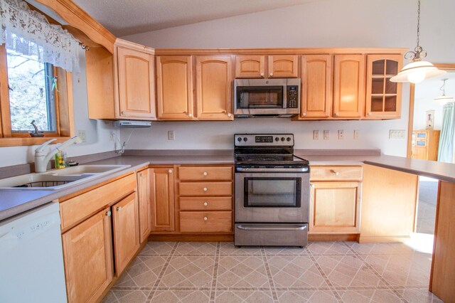 kitchen with light brown cabinets, sink, stainless steel appliances, pendant lighting, and vaulted ceiling