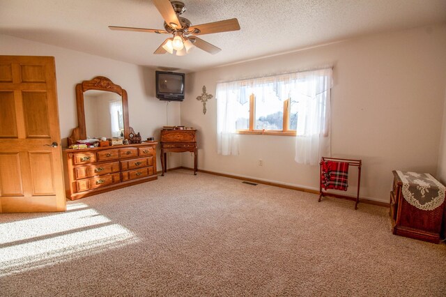 interior space with a textured ceiling, light colored carpet, and ceiling fan