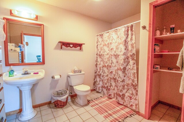 bathroom featuring tile patterned flooring, a shower with curtain, toilet, and sink