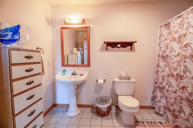 bathroom featuring tile patterned floors, curtained shower, and toilet